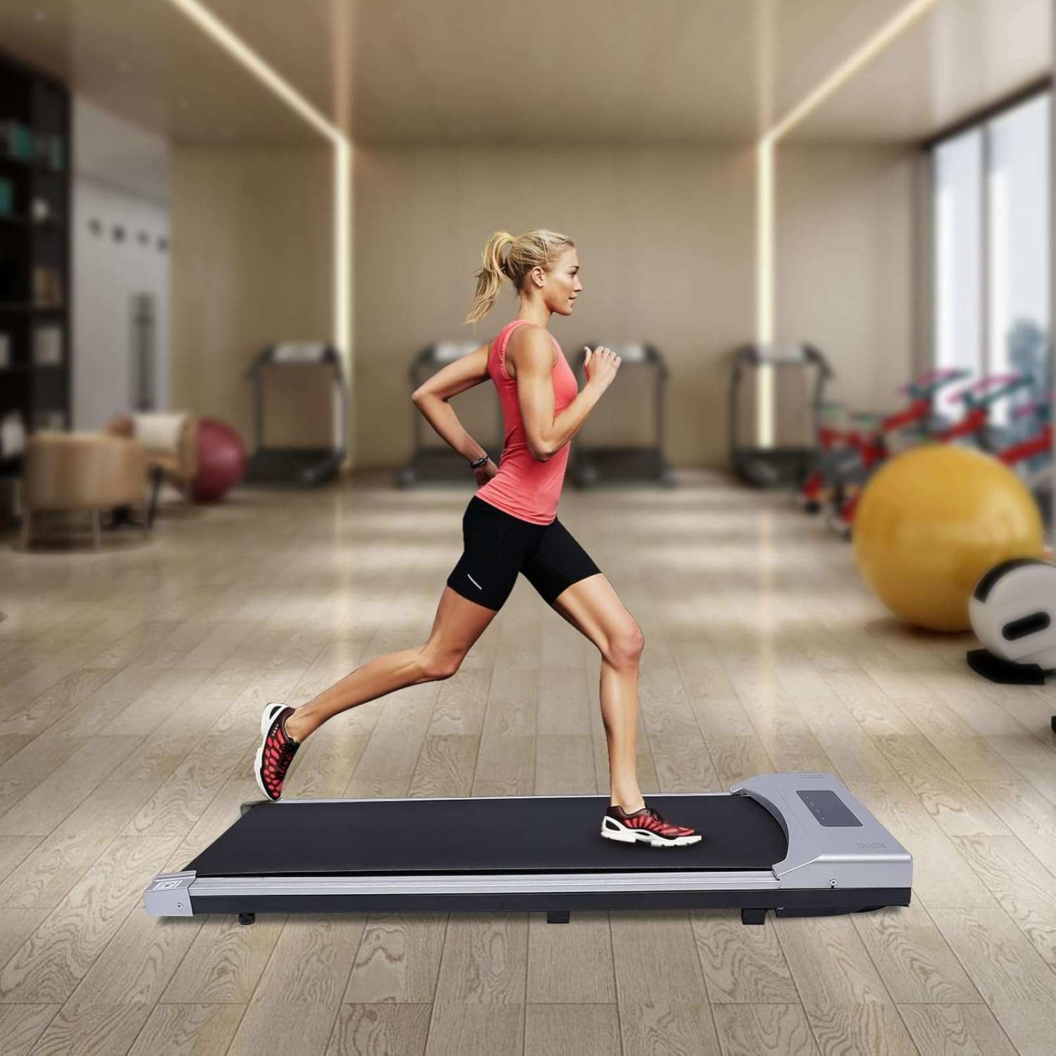Woman jogging on a portable under desk electric treadmill in a modern gym