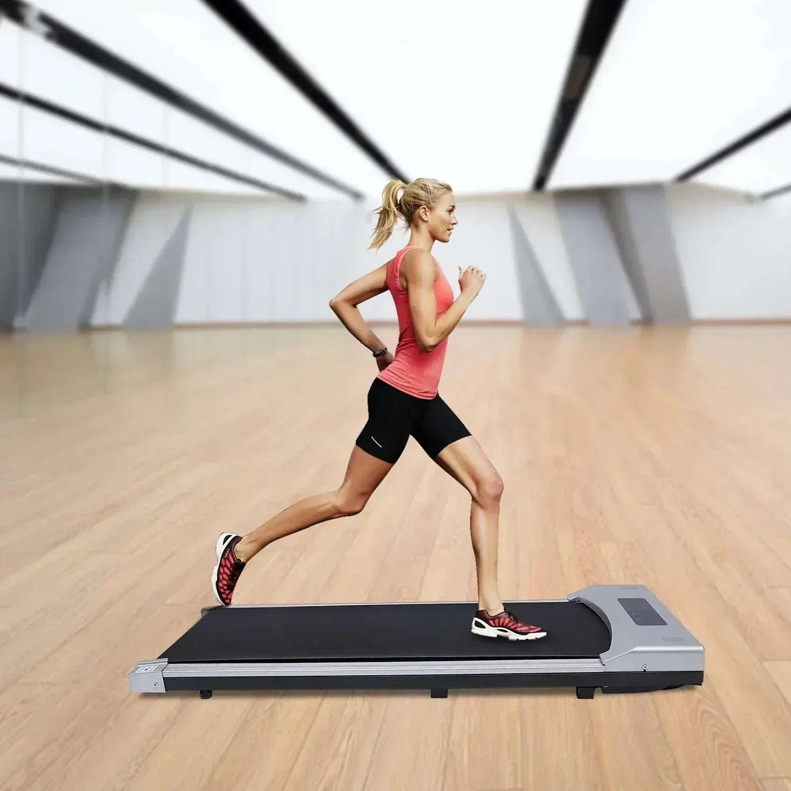 Woman running on a portable electric treadmill under desk walking pad with remote in a spacious room